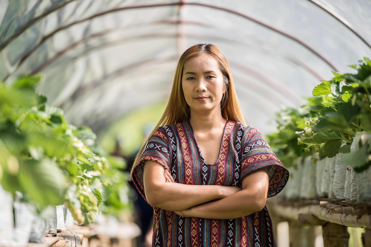 mooie boerenvrouw die aardbeienboerderij controleert foto