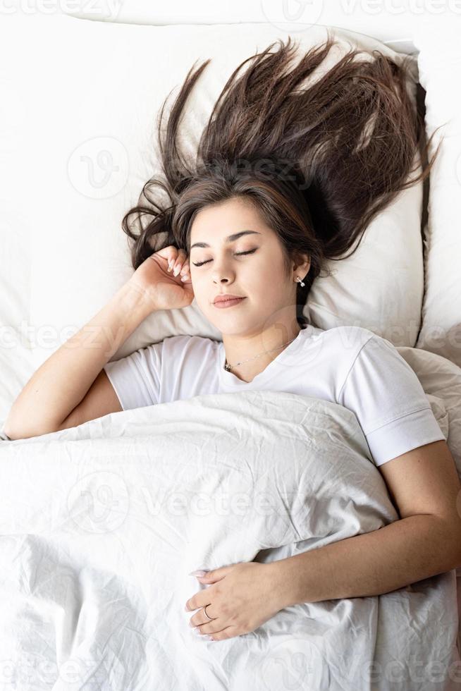 jonge mooie brunette vrouw slapen in bed foto
