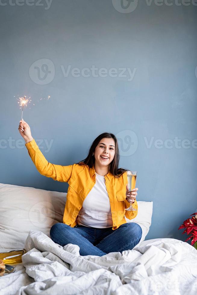 jonge brunette vrouw zittend in het bed champagne drinken met een sterretje foto