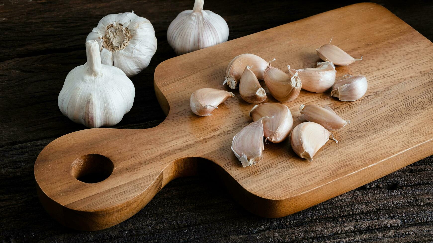 biologisch rauw knoflook lamp, knoflook kruidnagel Aan een houten snijdend bord Aan een houten tafel en knoflook kruidnagel van voedsel ingrediënten foto