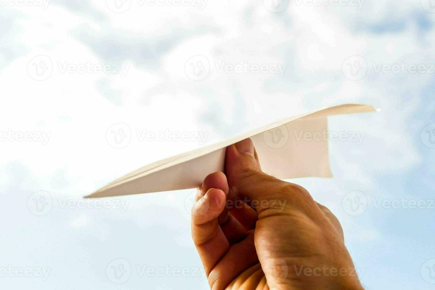 een persoon Holding een papier vliegtuig in de lucht foto