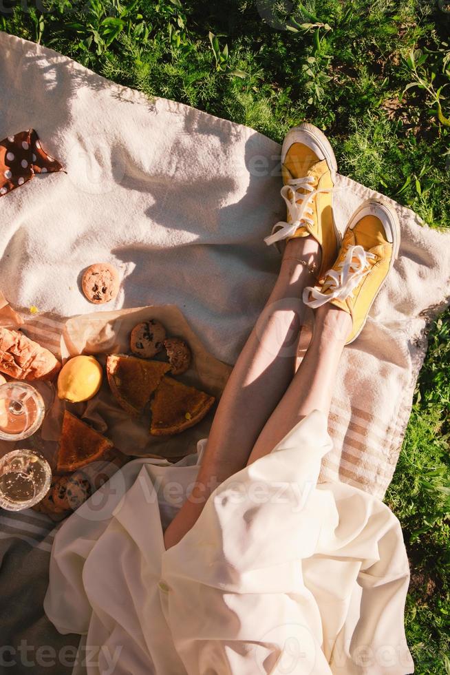 vrouwenbenen op deken die picknicken op zonsondergang eten drinken foto