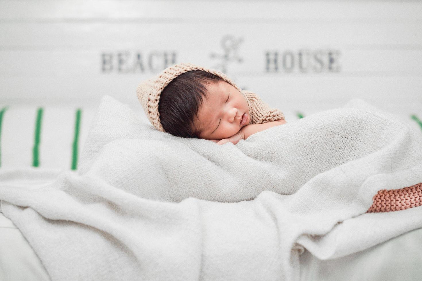 schattige pasgeboren baby die vredig op een witte deken slaapt foto