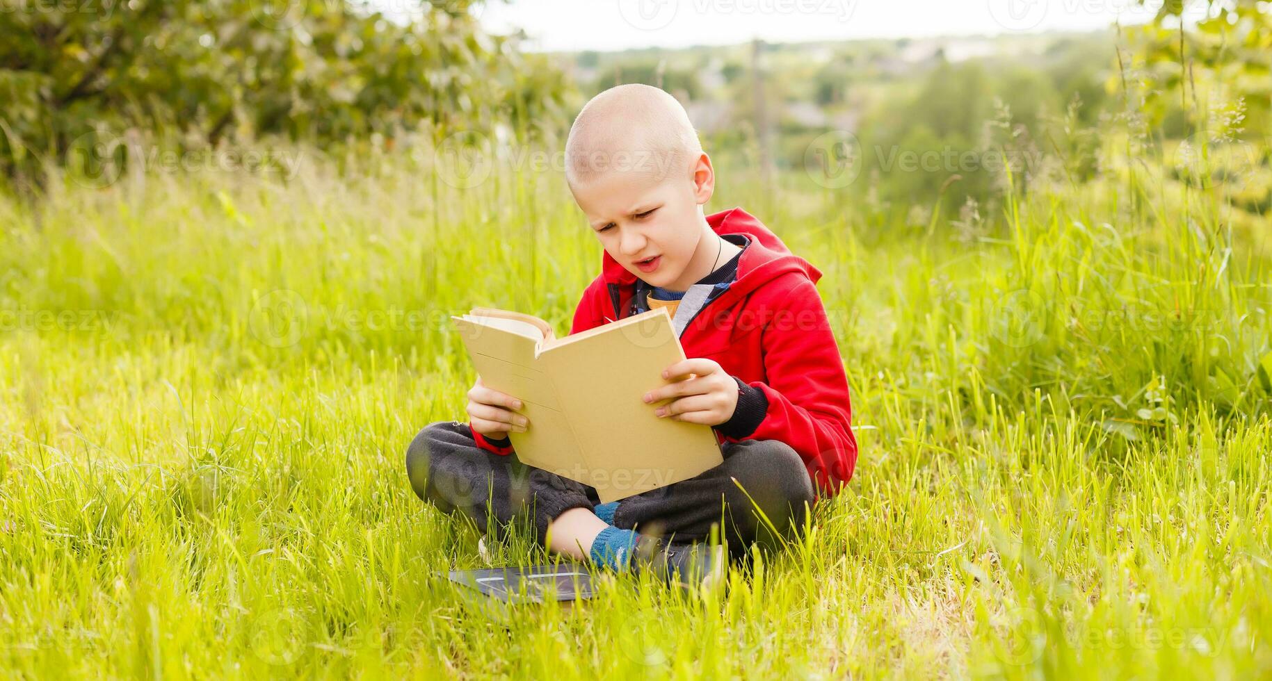 portret van een jongen zittend met een boek in de park foto