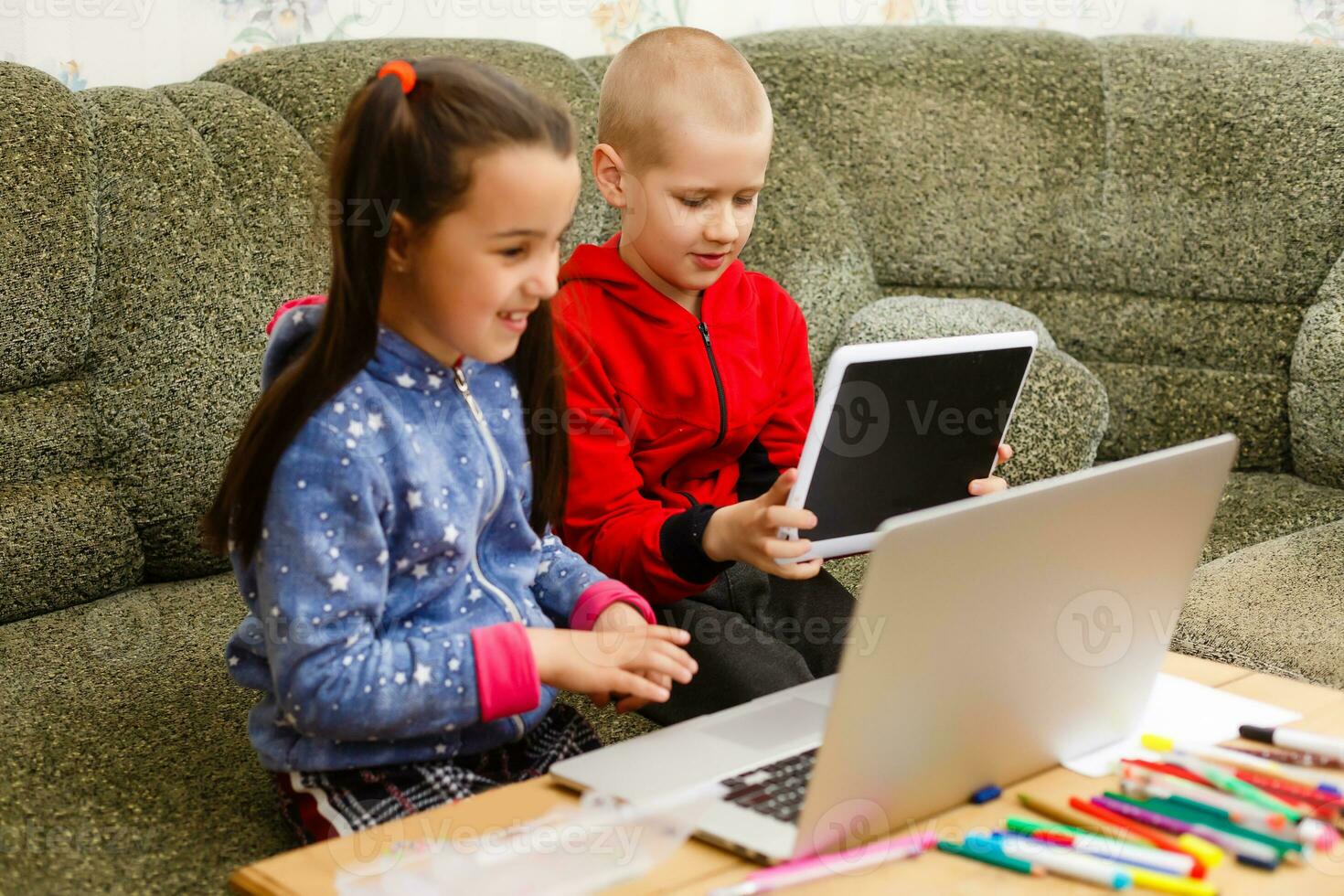 afstand aan het leren online onderwijs. school- jongen en meisje aan het studeren Bij huis met laptop notitieboekje en aan het doen huiswerk. zittend Bij een tafel foto