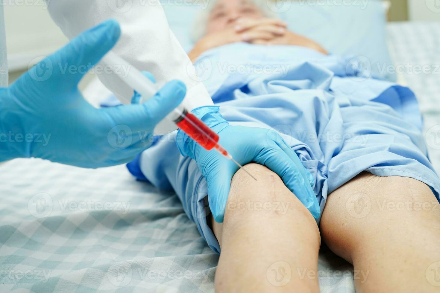 Aziatische arts injecteert hyaluronzuur bloedplaatjes rijk plasma in de knie van senior vrouw om te lopen zonder pijn. foto