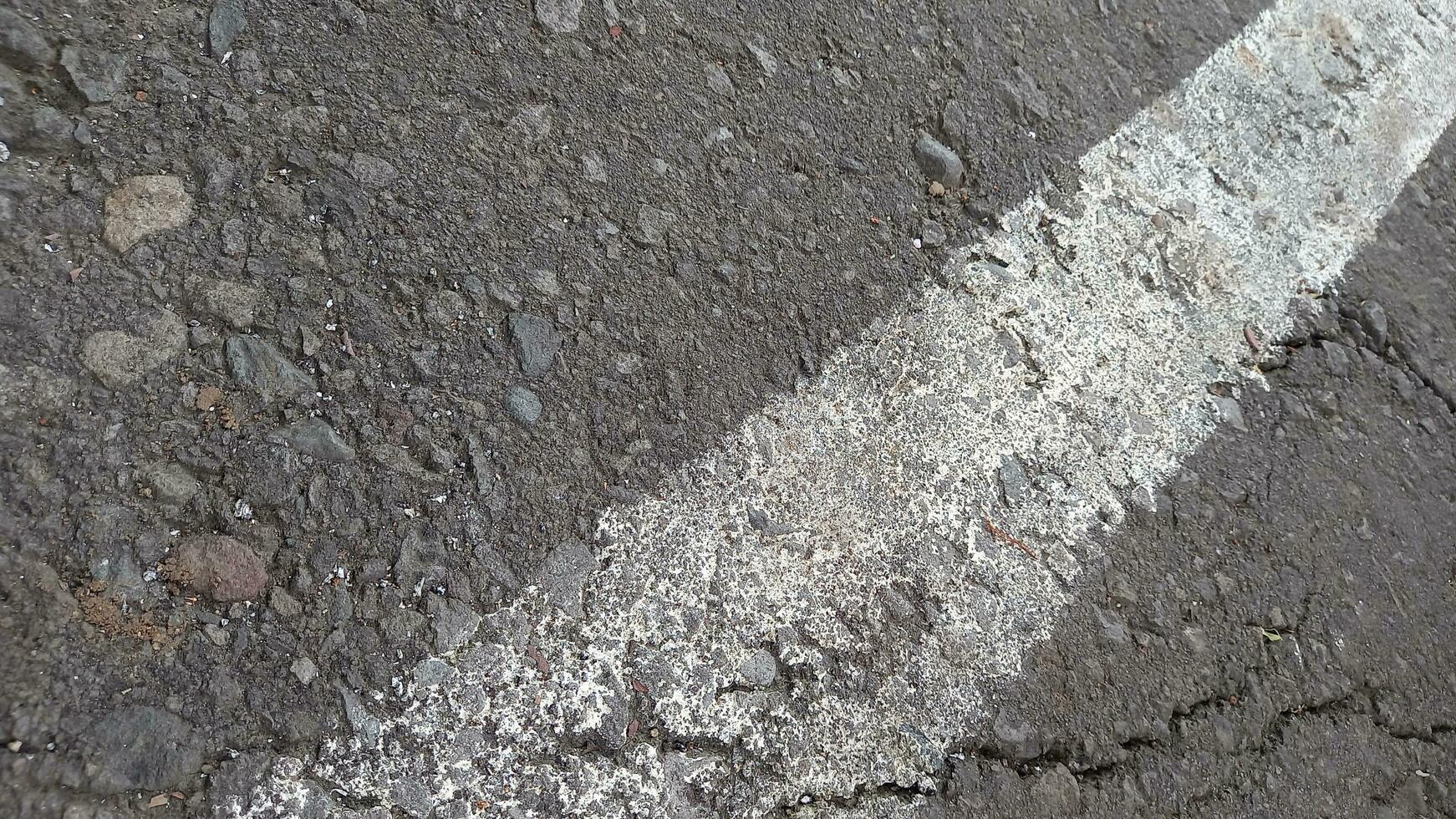 grijs asfalt met wit lijnen. ruw cement weg oppervlak. gebarsten asfalt weg achtergrond. foto