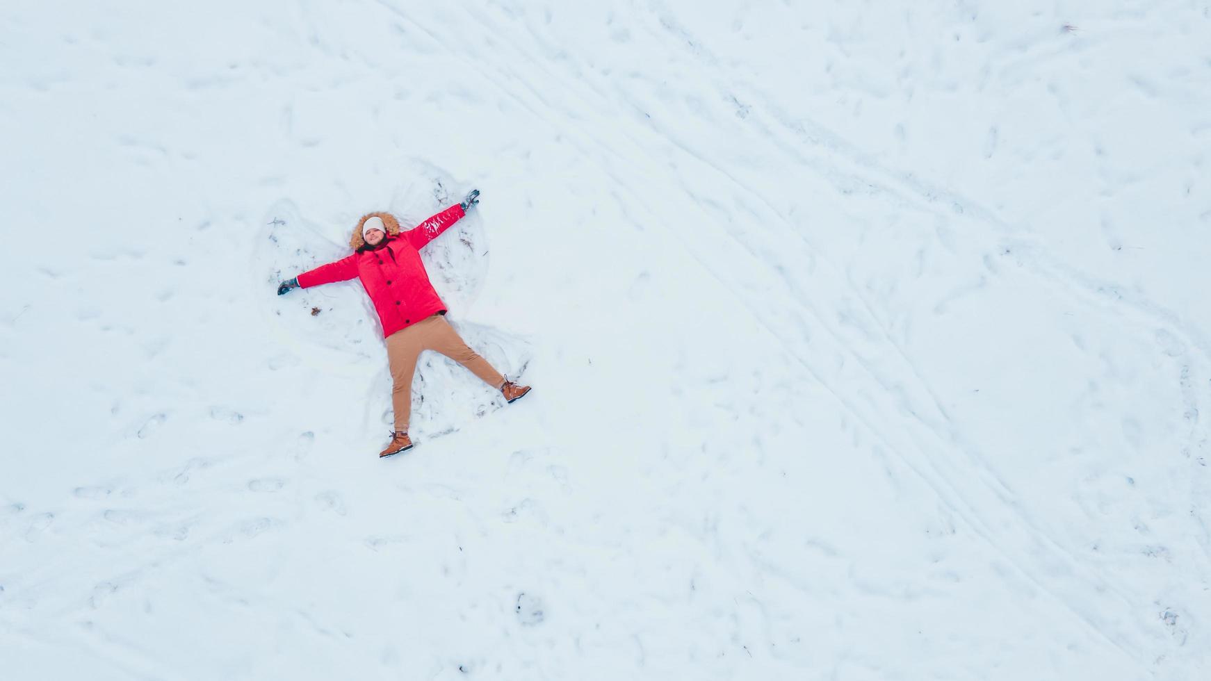 bovenaanzicht van man die sneeuwengel maakt foto