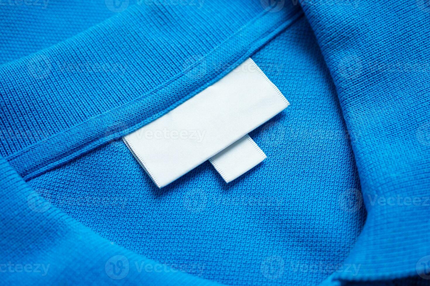 blanco wit wasserij zorg kleren etiket Aan blauw overhemd kleding stof structuur achtergrond foto