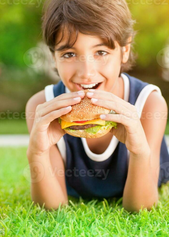 gelukkig jongen aan het eten hamburger foto