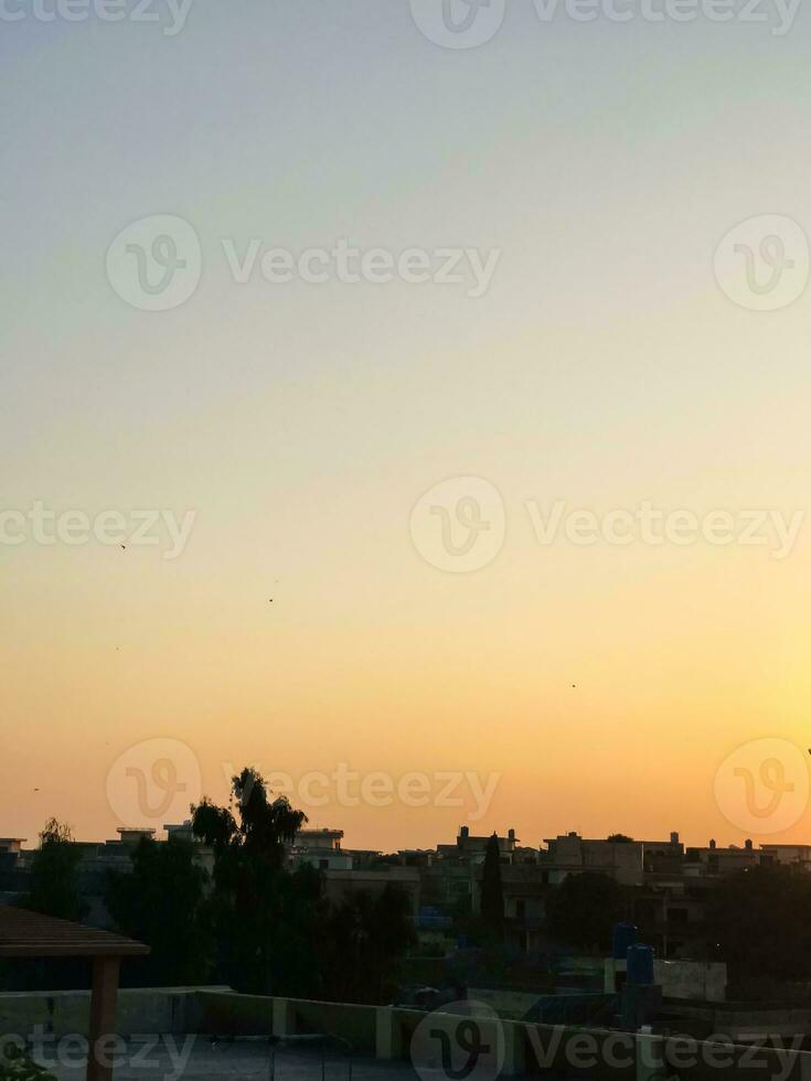 een zonsondergang over- een stad met vogelstand vliegend in de lucht foto