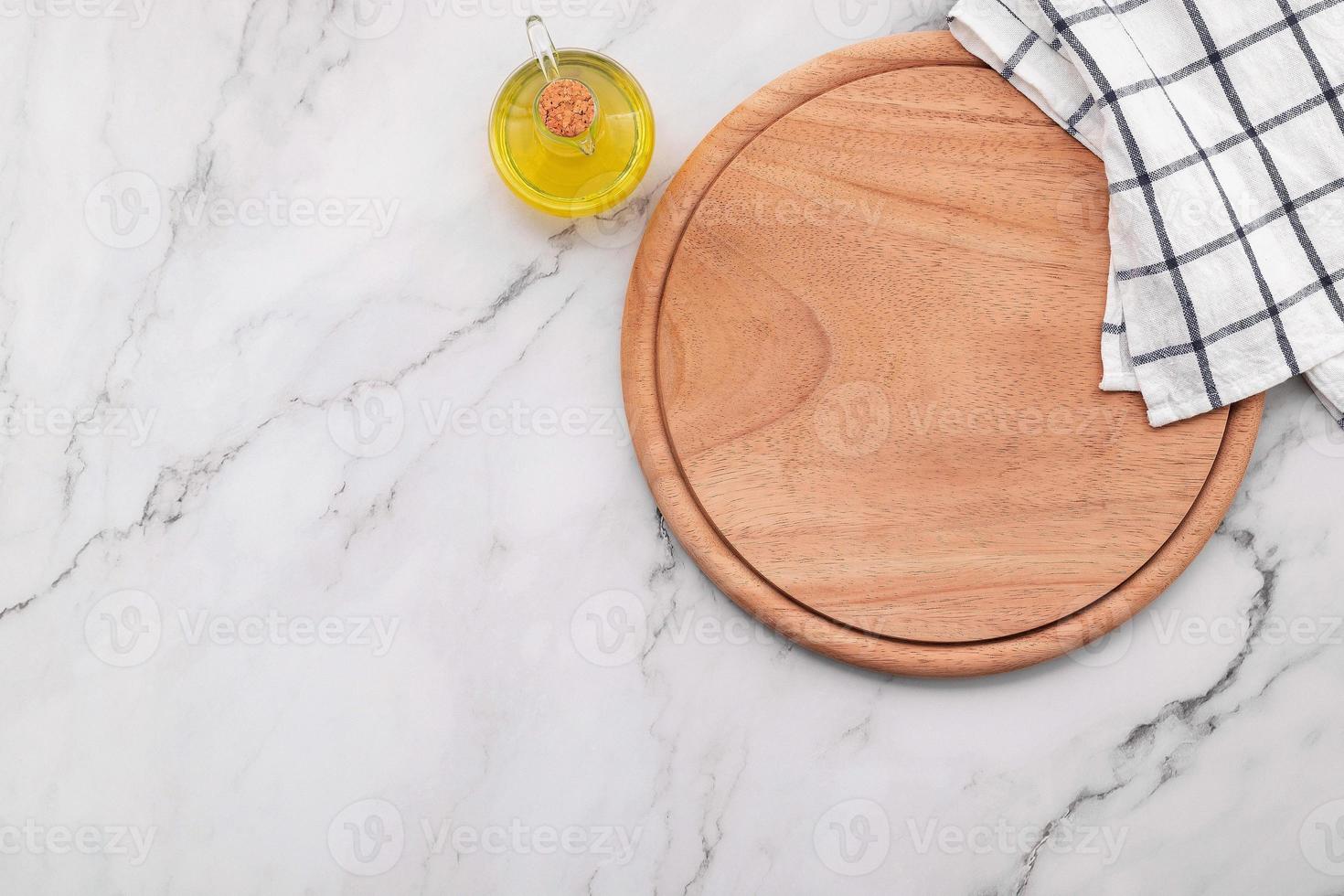 lege houten pizzaschotel met servet opgezet op marmeren stenen keukentafel. pizza bord en tafelkleed op witte marmeren achtergrond. foto