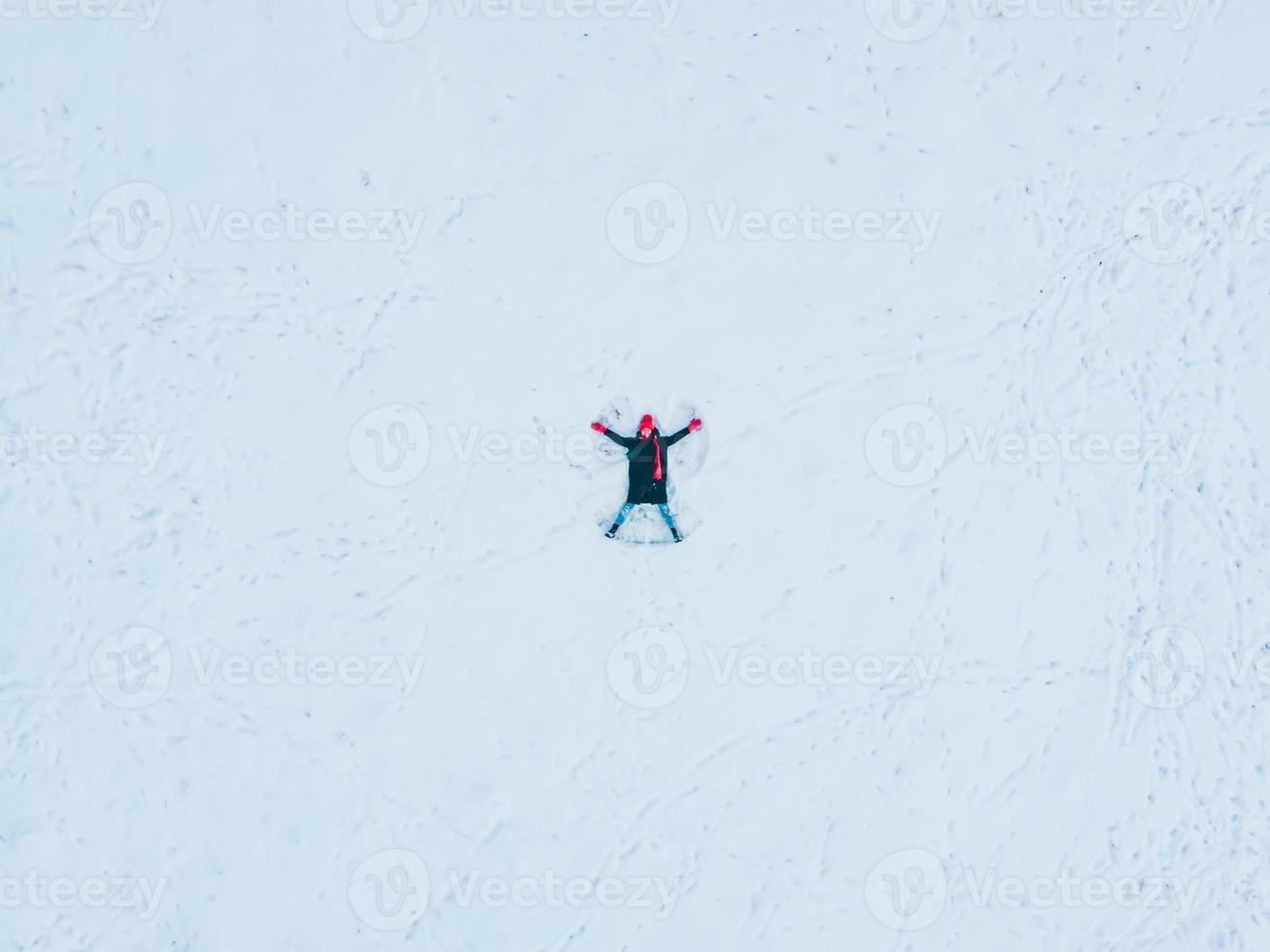 gelukkige vrouw die sneeuwengel maakt foto