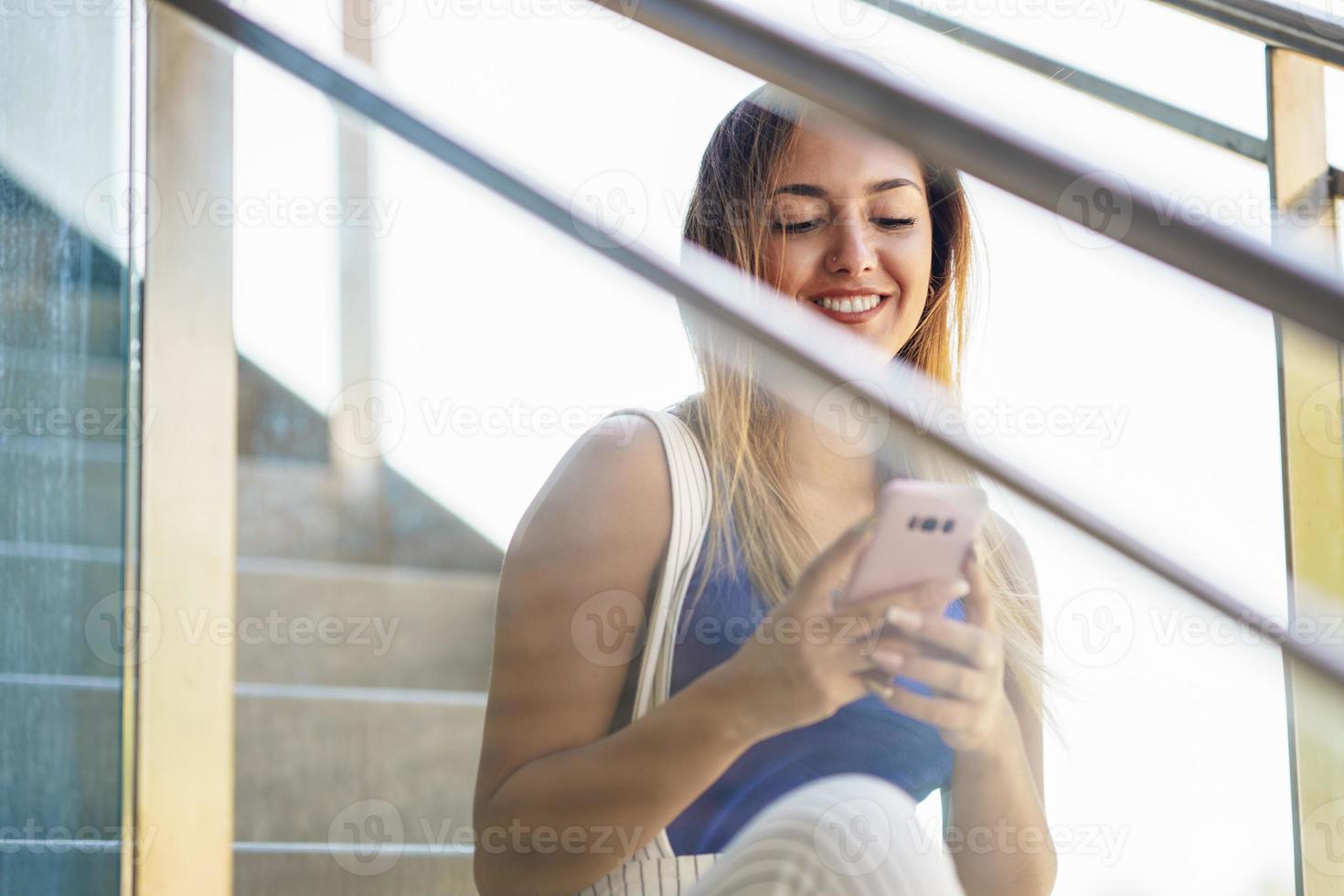 meisje dat een touchscreen-smartphone gebruikt die vrijetijdskleding draagt foto