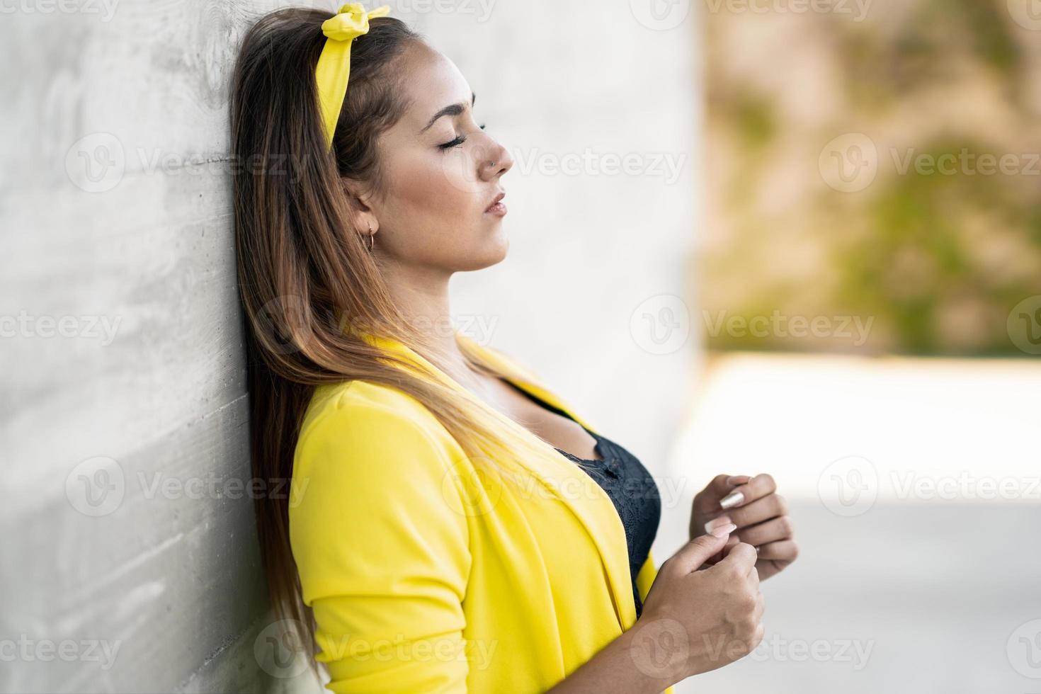 jonge vrouw die een gele jas en hoofdband draagt foto