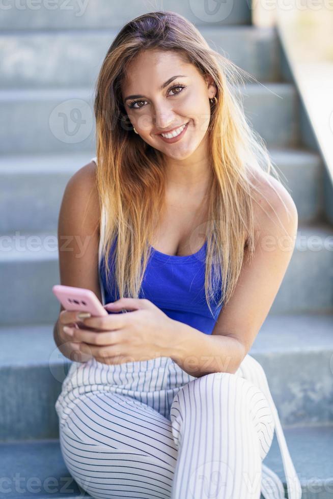 meisje dat een touchscreen-smartphone gebruikt die vrijetijdskleding draagt foto