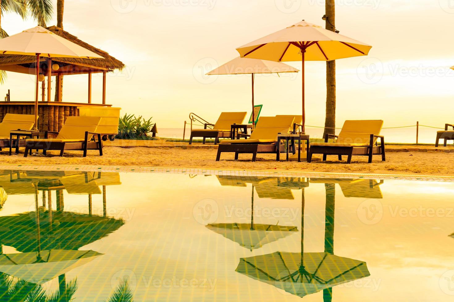 parasol en stoel rond zwembad in hotelresort met zonsopgang in de ochtend foto