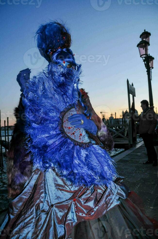 een vrouw gekleed in een blauw en Purper kostuum is staand Aan de straat foto
