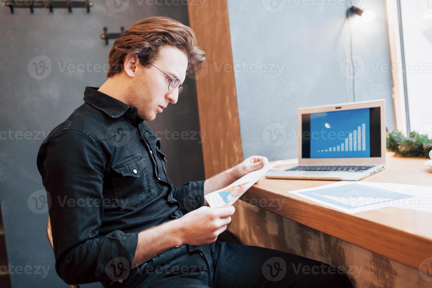 zakenman met behulp van laptop met tablet en pen op houten tafel in coffeeshop met een kopje koffie. een ondernemer die als freelancer zijn bedrijf op afstand bestuurt. foto