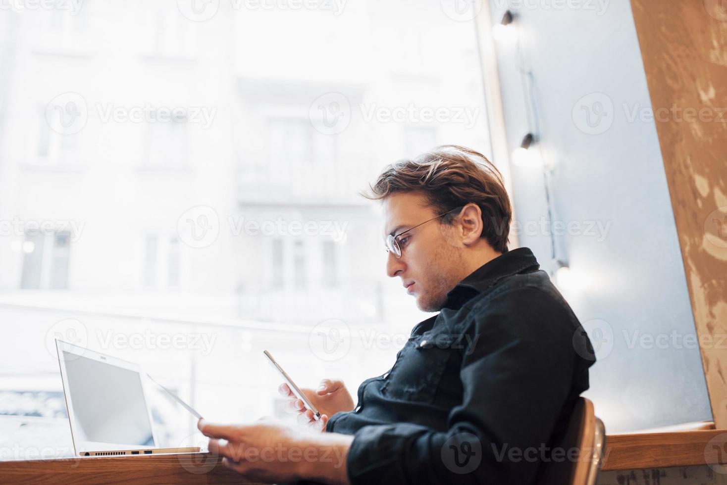 ontspannen jonge professional surfen op het internet op zijn laptop in een café foto