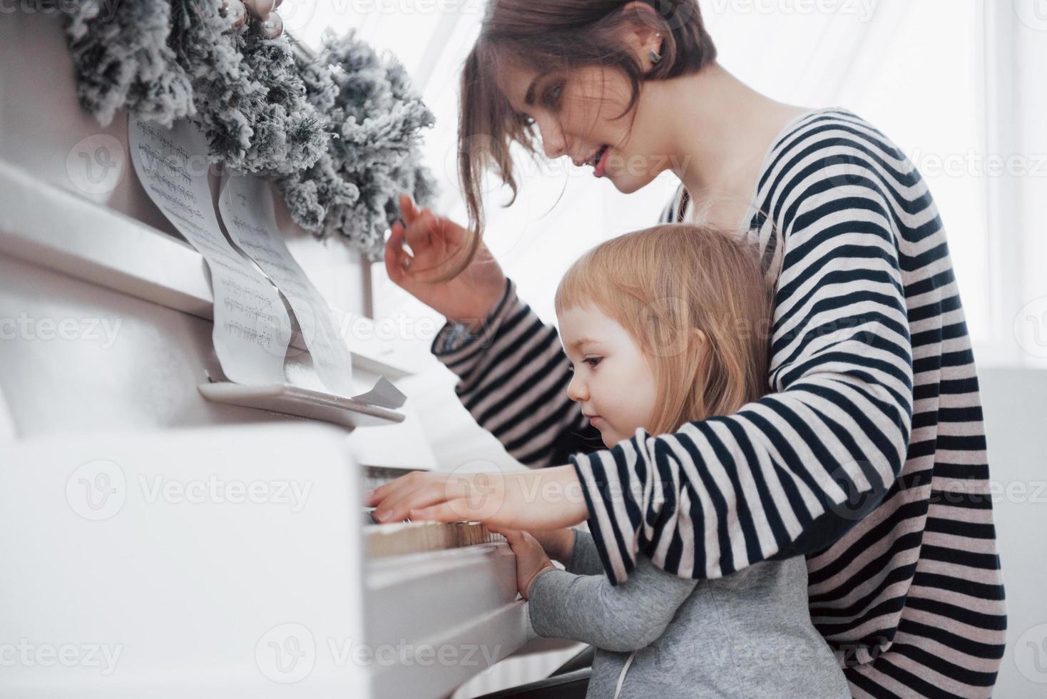 moeder en dochter spelen witte piano, close-up wiew foto