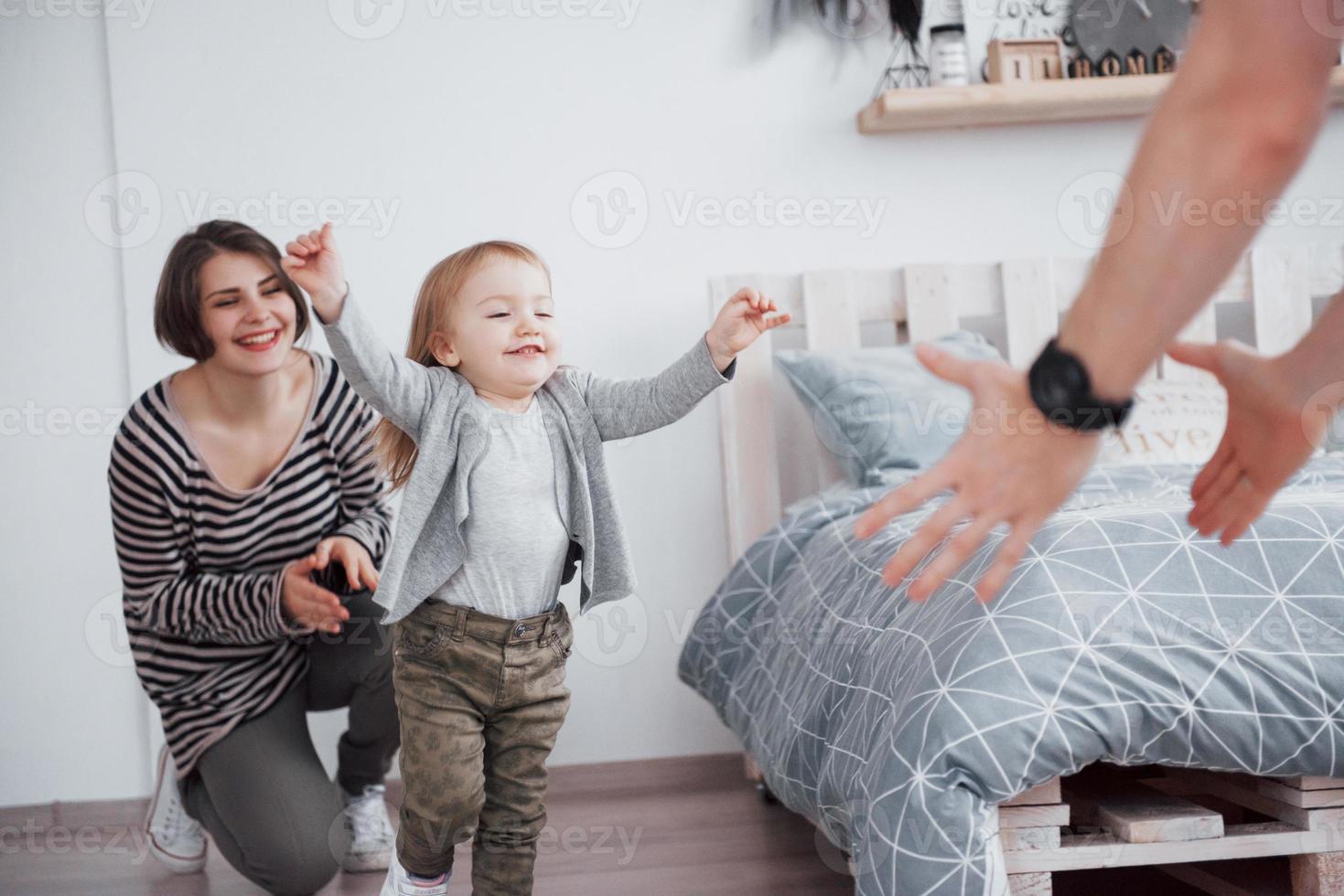 gelukkige familie heeft thuis plezier. moeder, vader en dochtertje met knuffel genieten van het samenzijn foto