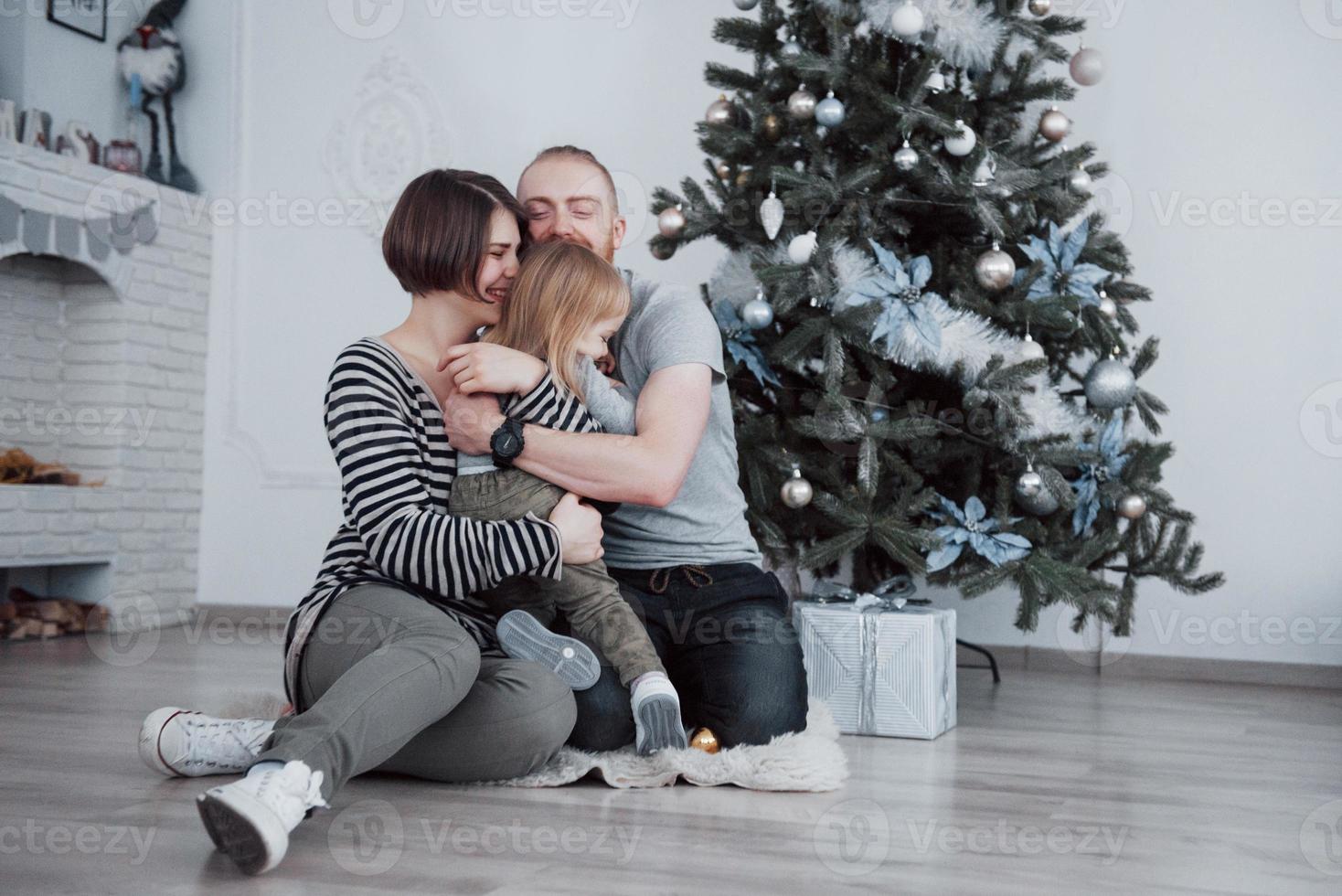 gelukkige familie met kerstmis in de ochtend die geschenken samen opent in de buurt van de dennenboom. het concept van gezinsgeluk en welzijn foto