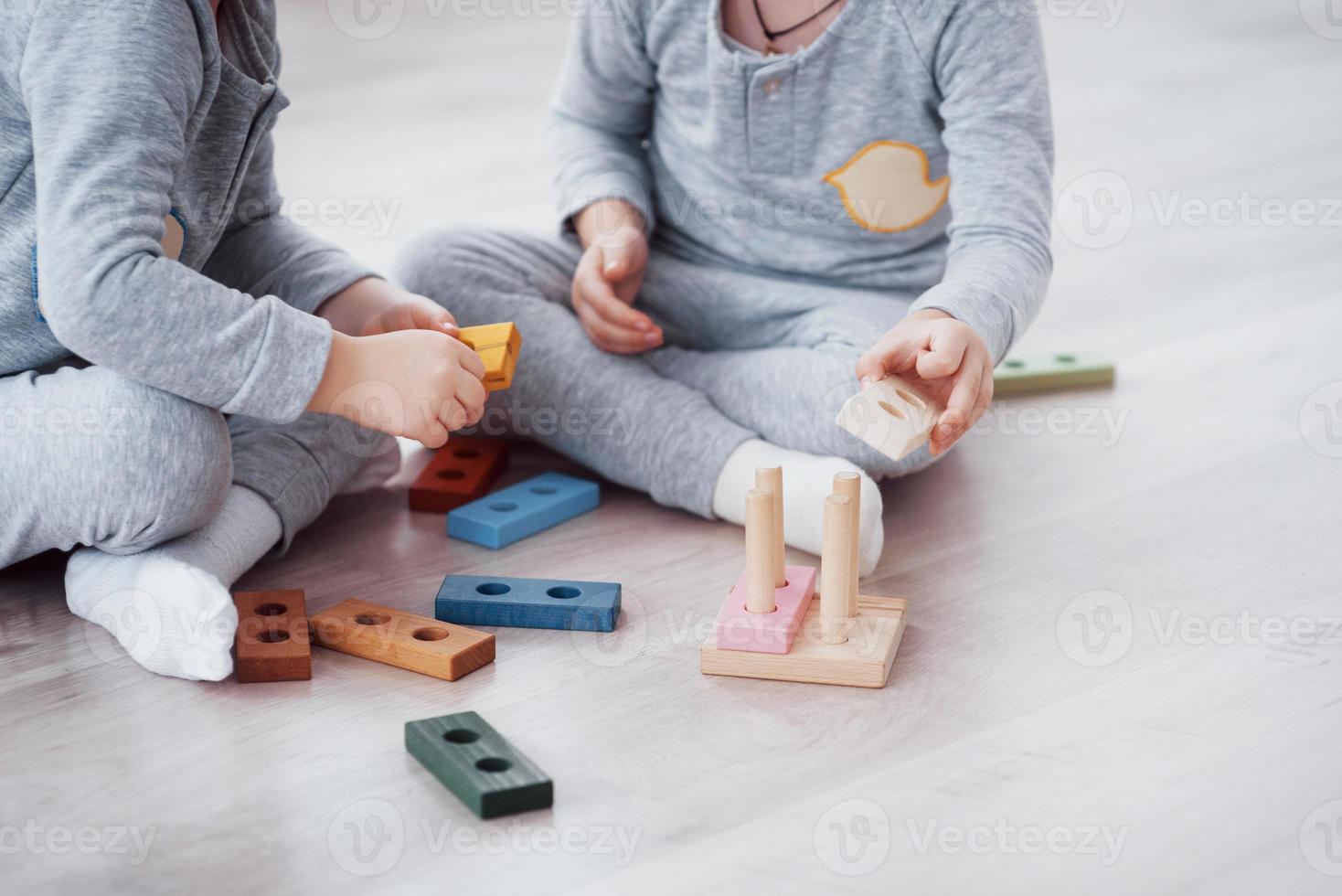 kinderen spelen met een speelgoedontwerper op de vloer van de kinderkamer. twee kinderen spelen met kleurrijke blokken. educatieve spelletjes voor de kleuterschool foto
