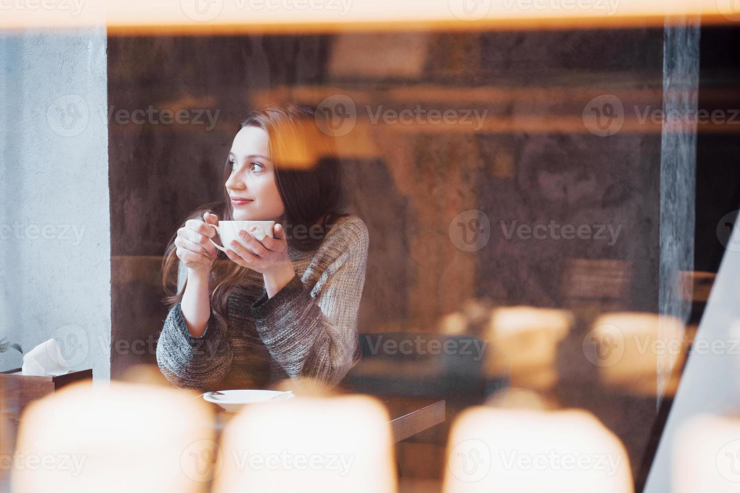 lachende vrouw in café met behulp van mobiele telefoon en sms'en in sociale netwerken, alleen zittend foto