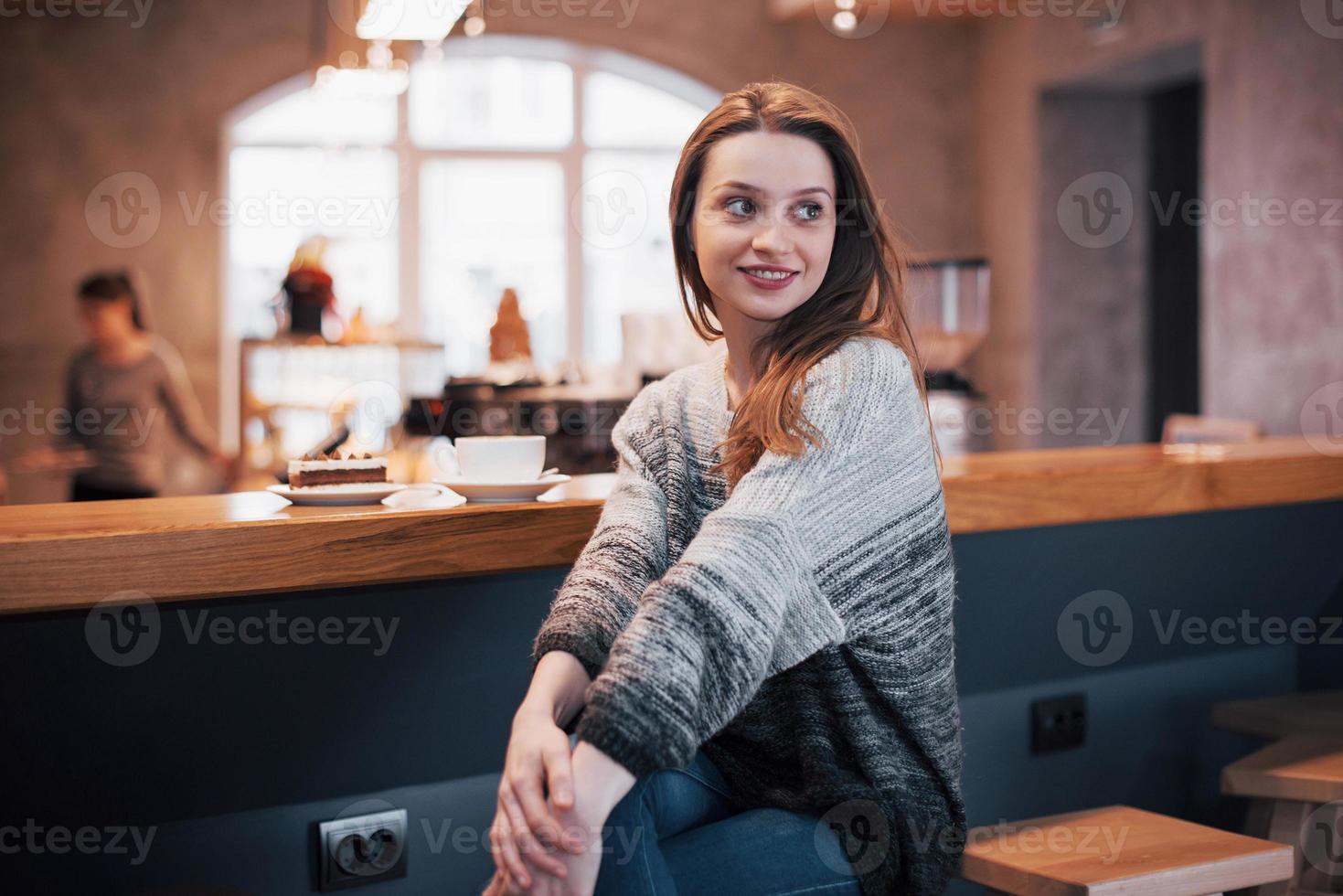 mooie jonge vrouw zit in het café met een kopje thee foto