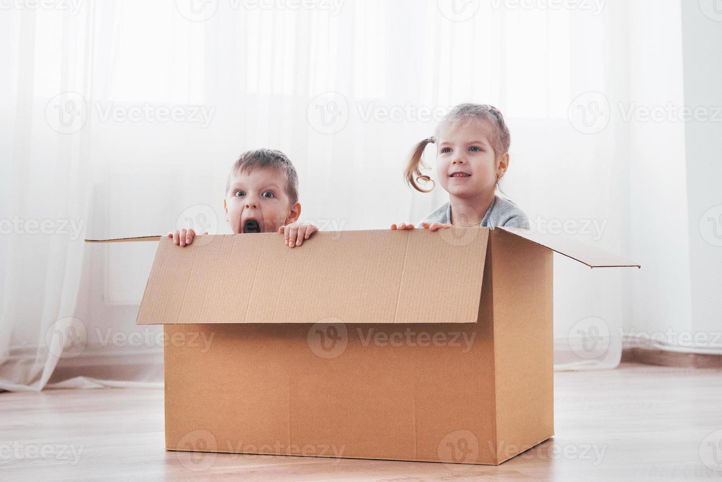 twee kleine kinderen jongen en meisje spelen in kartonnen dozen. concept foto. kinderen hebben plezier foto