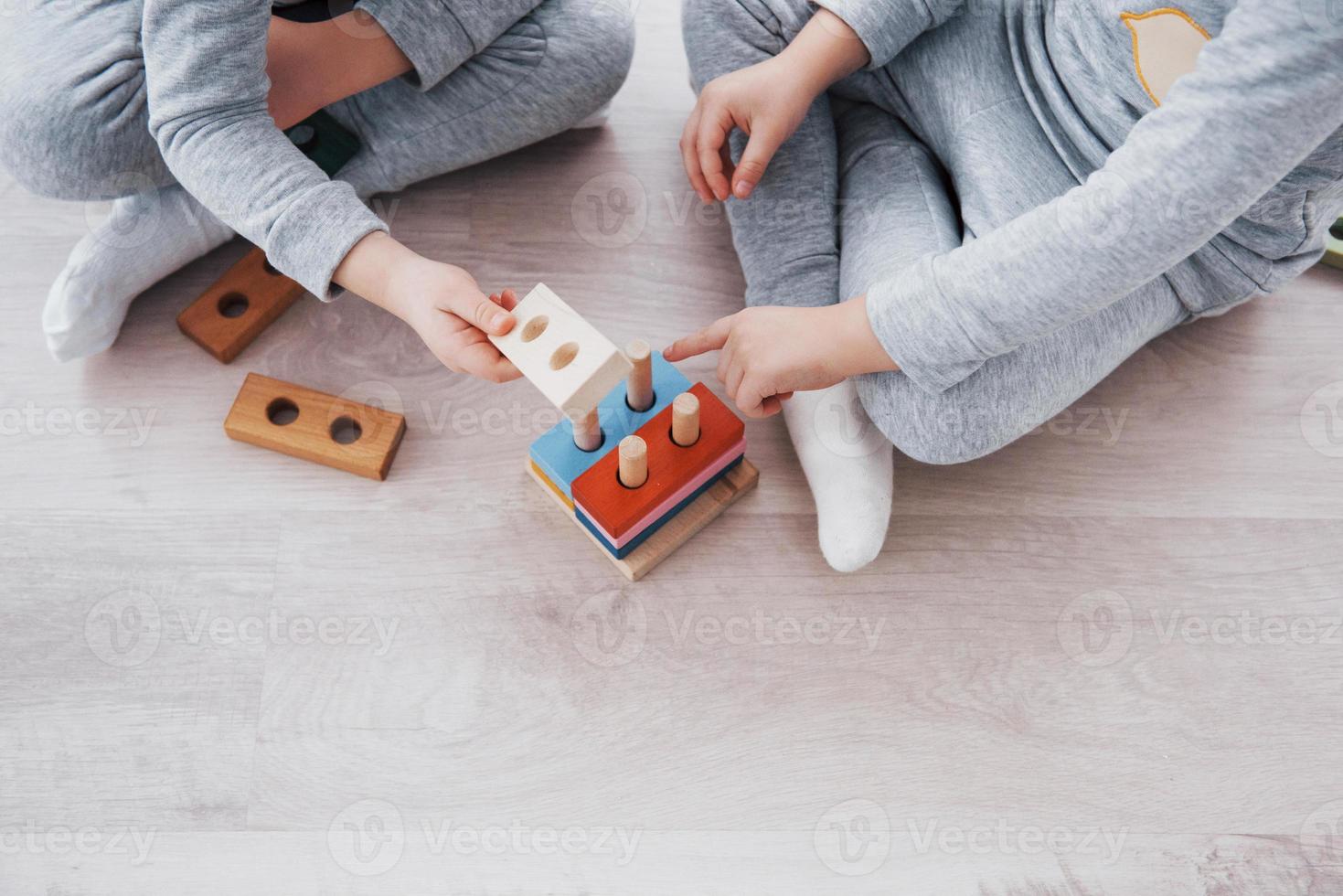 kinderen spelen met een speelgoedontwerper op de vloer van de kinderkamer. twee kinderen spelen met kleurrijke blokken. educatieve spelletjes voor de kleuterschool foto