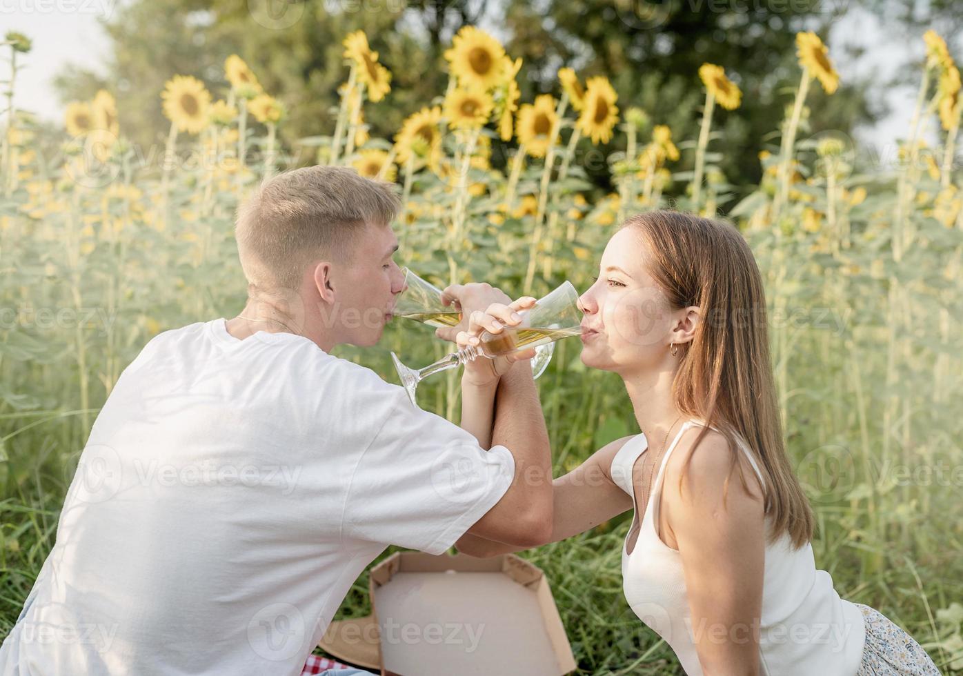 jong koppel met picknick op zonnebloemveld bij zonsondergang foto