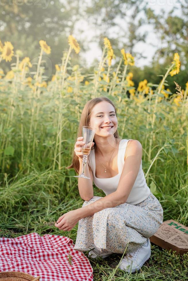 jonge vrouw met picknick op zonnebloemveld bij zonsondergang foto