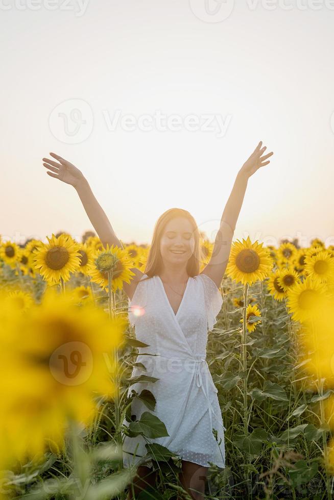 jonge mooie vrouw tussen zonnebloemen in zonsondergang foto