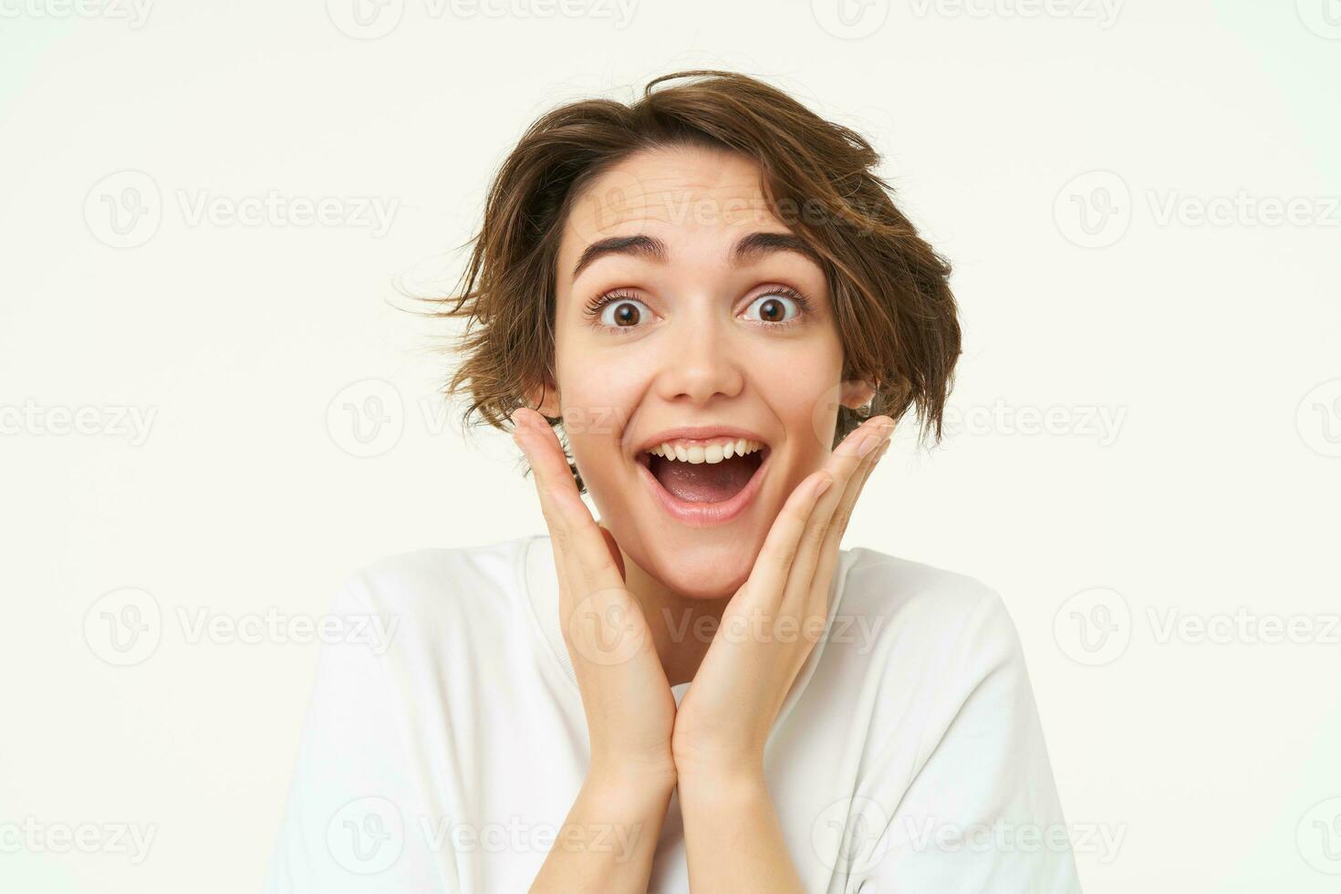 portret van meisje met verrast gezicht, maakt geschokt uitdrukking, staat over- wit achtergrond foto