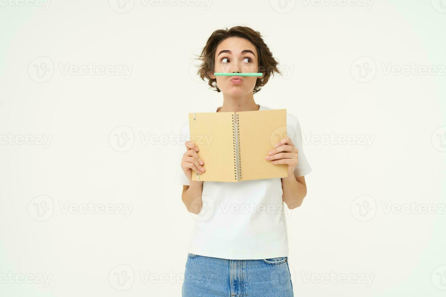 schattig brunette meisje, spelen met pen, Holding potlood met haar lip, Holding planner, schrijven in dagboek, poseren over- wit studio achtergrond foto