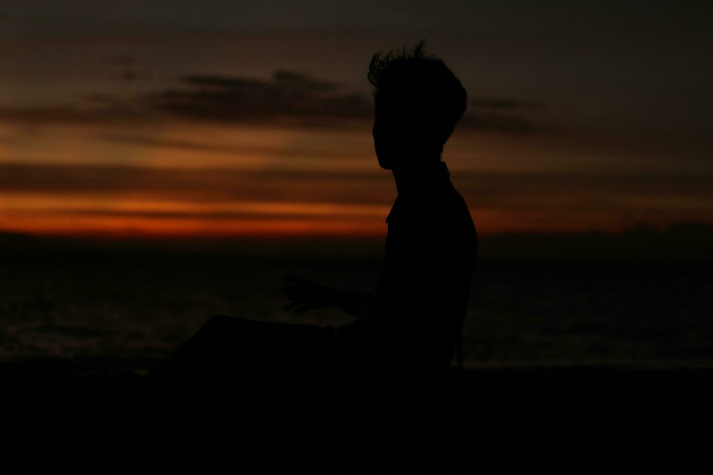 silhouet van een jong Mens staand door de meer genieten van de zonsondergang. vredig atmosfeer in natuur foto