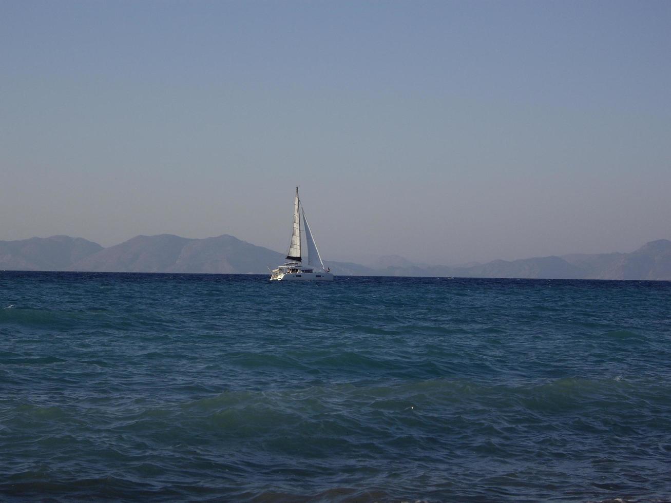 een zeilboot vaart in de egeïsche zee langs het eiland rhodos in griekenland foto