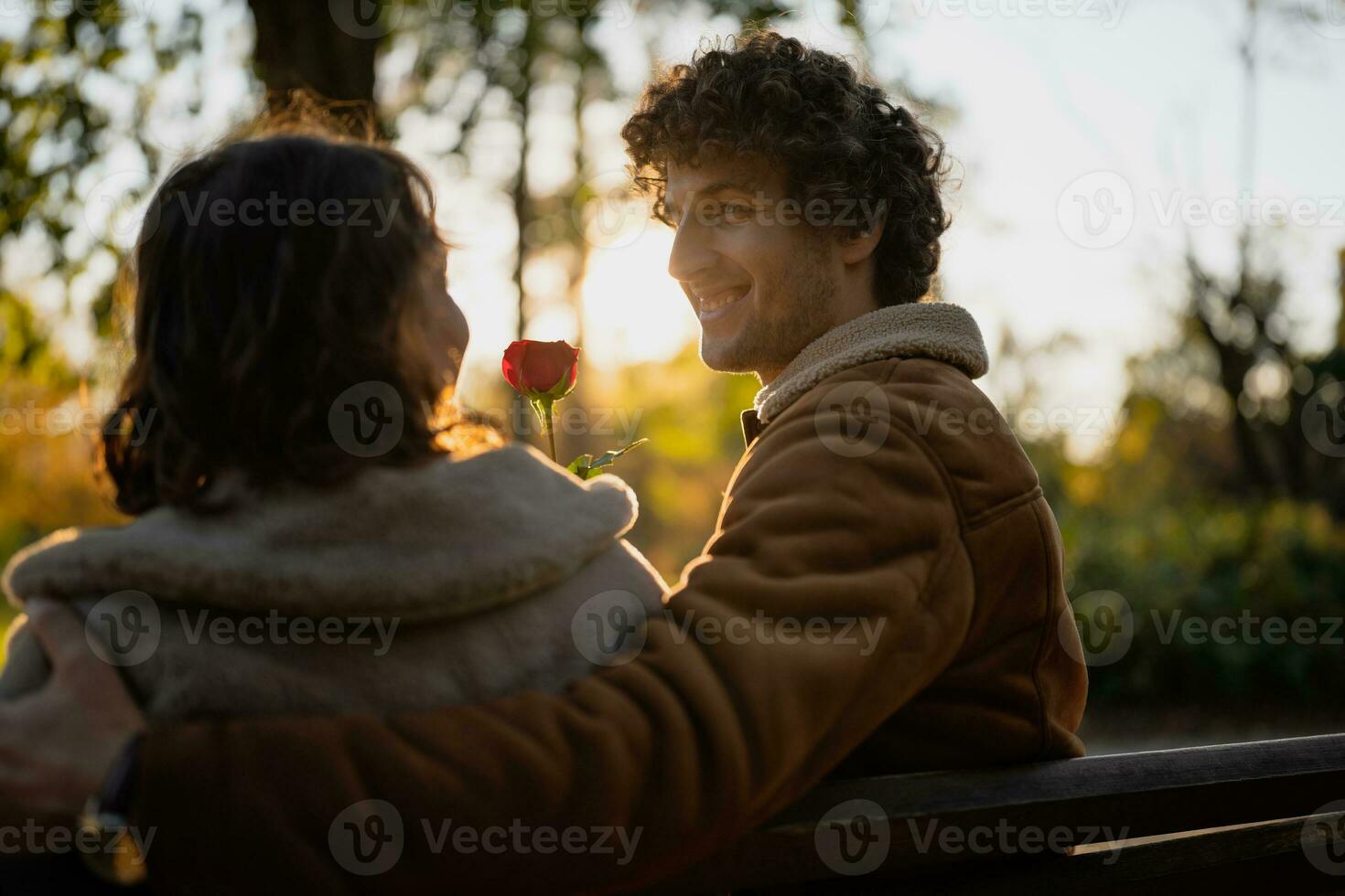gelukkig liefhebbend paar genieten van hun tijd samen in park. Mens is geven roos naar zijn vrouw. foto