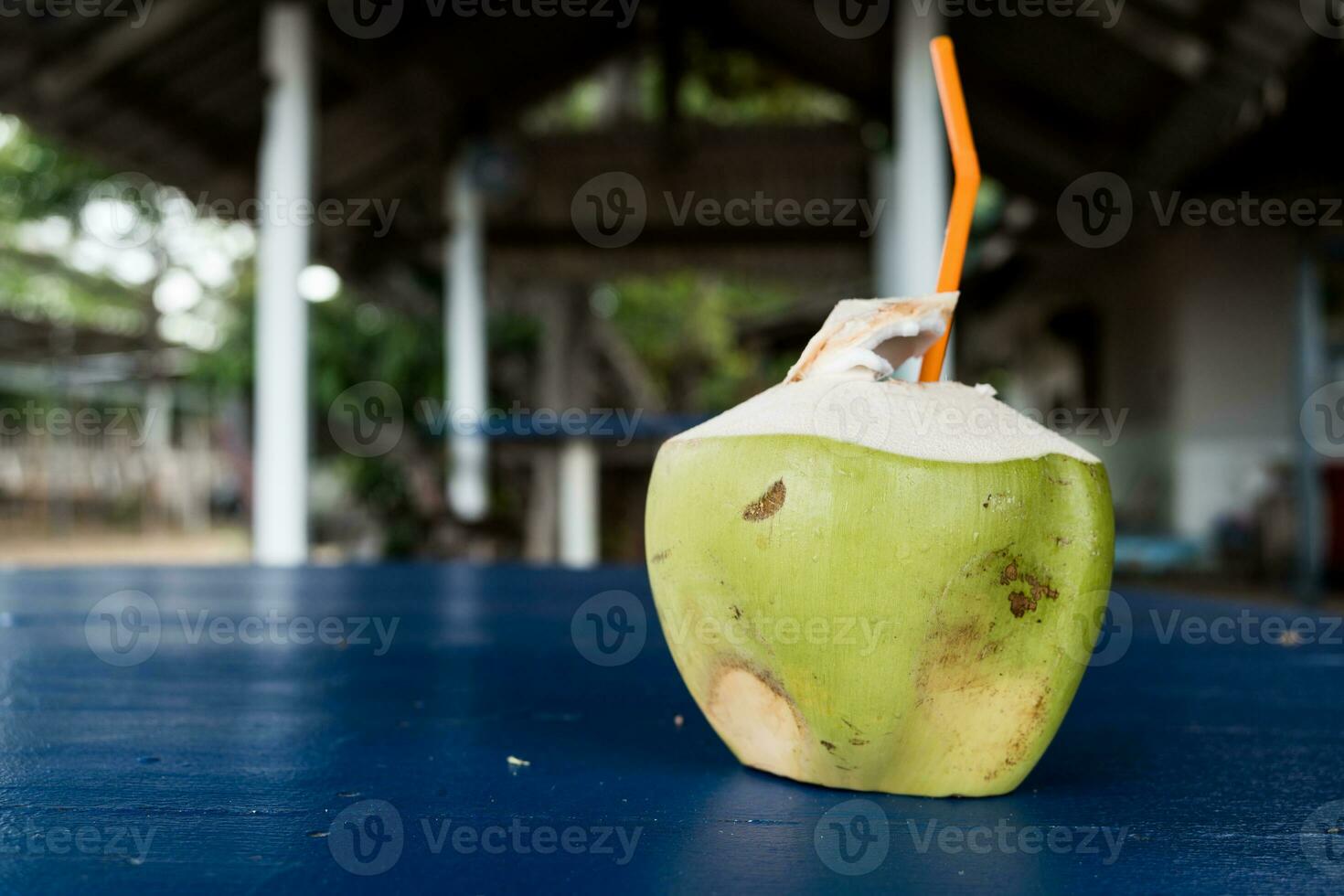 kokosnoot fruit drinken met een oranje plastic rietje. vers kokosnoot drankje. echt kokosnoot drinken foto