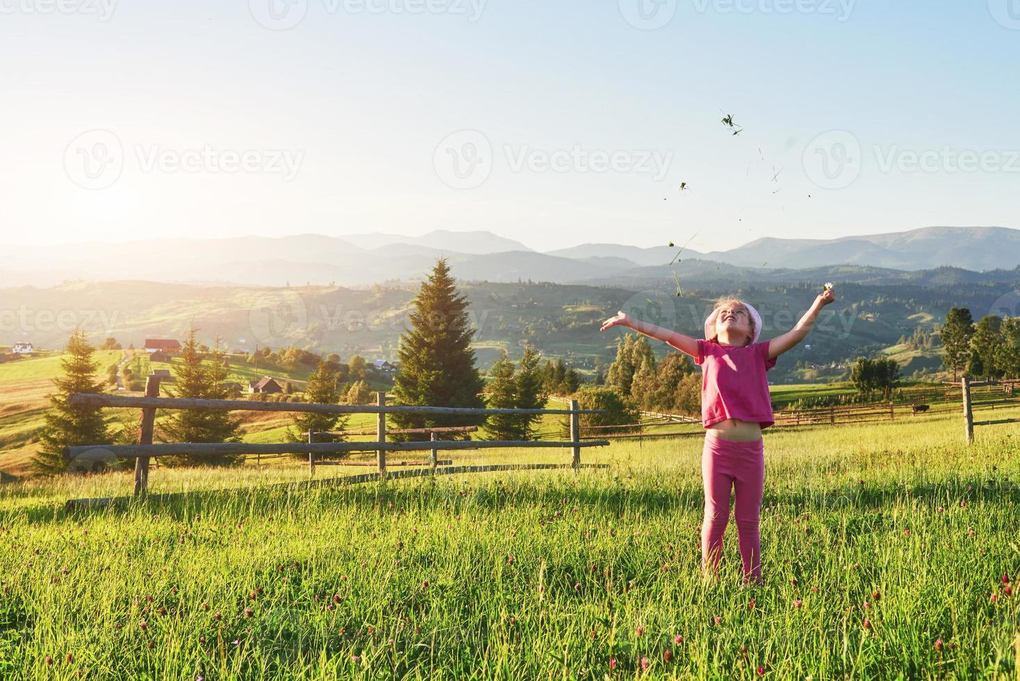 schattig gelukkig klein babymeisje buiten spelen in het gazon en het bewonderen van de bergen. kopieer ruimte voor uw tekst foto