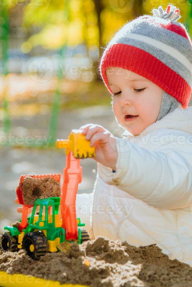 weinig kind Toneelstukken in de zandbak met speelgoed foto