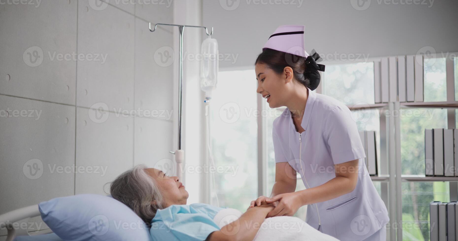 portret van jong verpleegster geruststellend een senior vrouw geduldig aan het liegen in ziekenhuis bed, verzorger en levensstijl concept foto