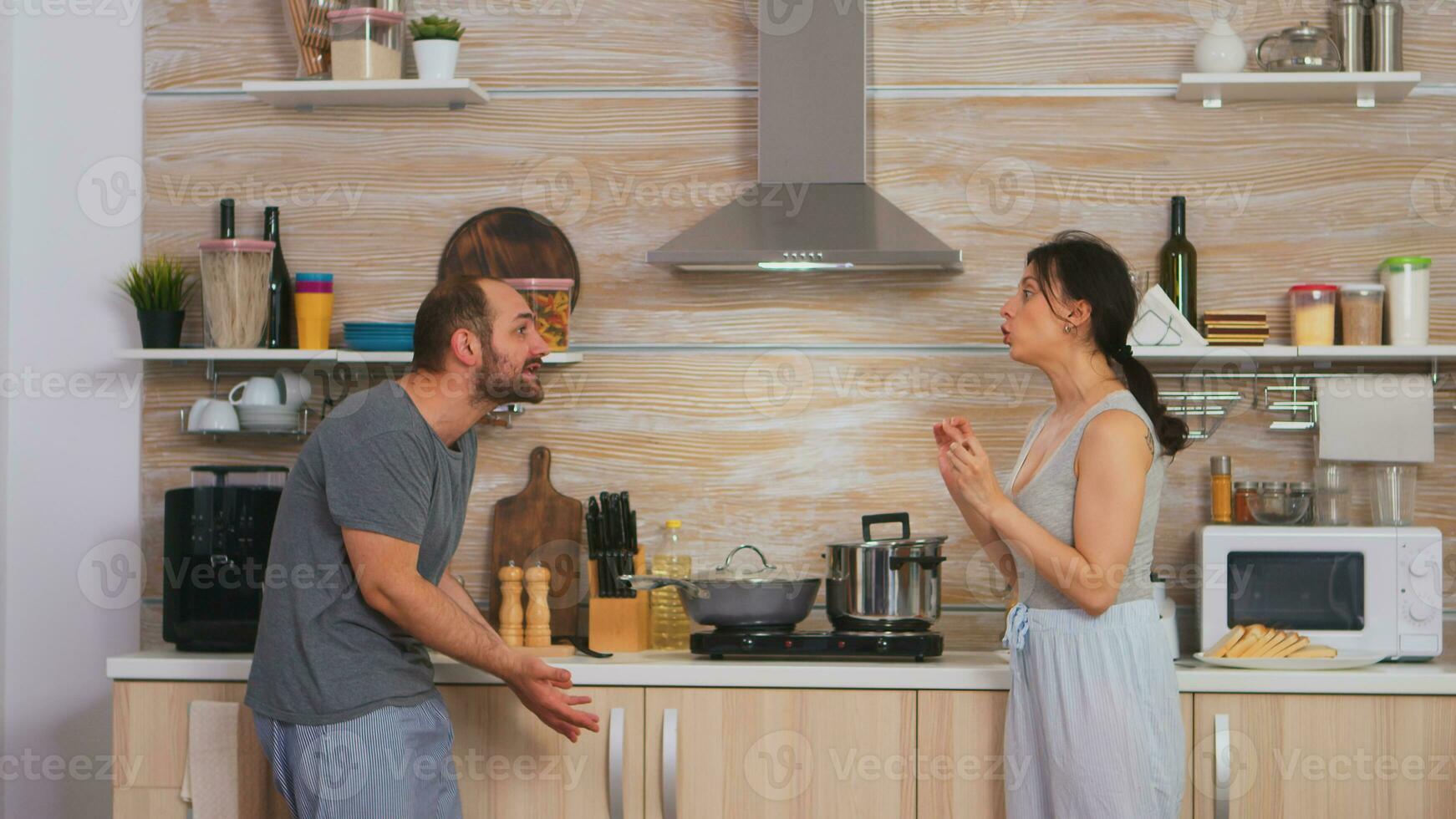 paar schreeuwen Bij elk andere in de keuken in de ochtend. jong paar ruzies in de keuken. Mens en vrouw schreeuwt in frustratie gedurende huis gesprek. foto