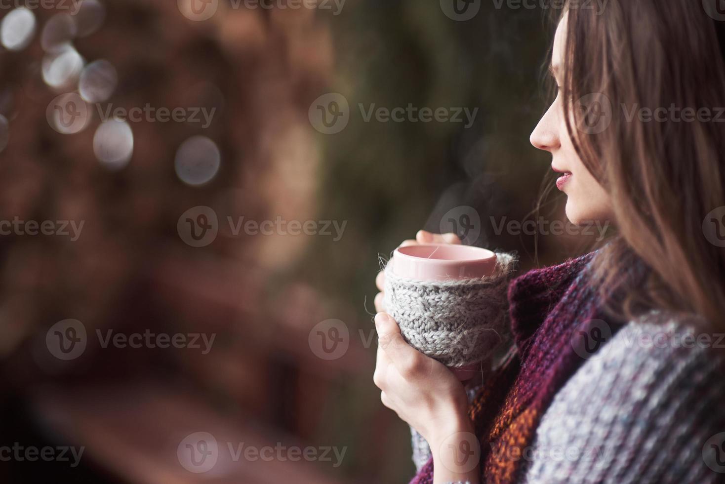 oman draagt warme gebreide kleding die buiten een kop hete thee of koffie drinkt foto