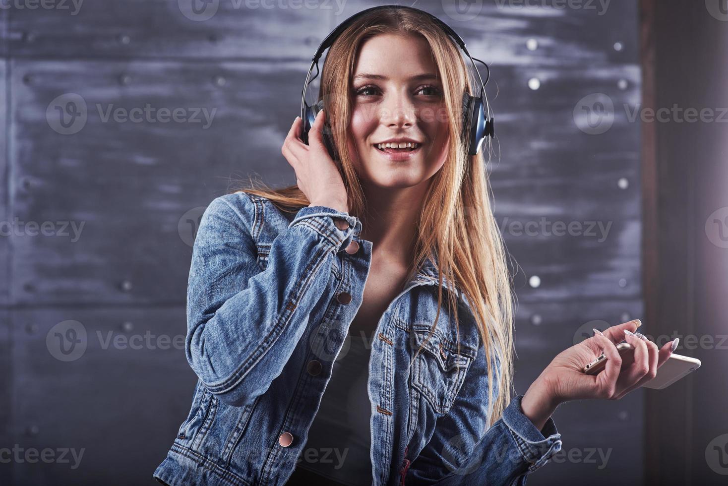 mode, kleding, mensen concept. close-up aantrekkelijke sexy jonge vrouw met jeans jasje. meisje poseert in de studio luistert naar muziek in een koptelefoon foto