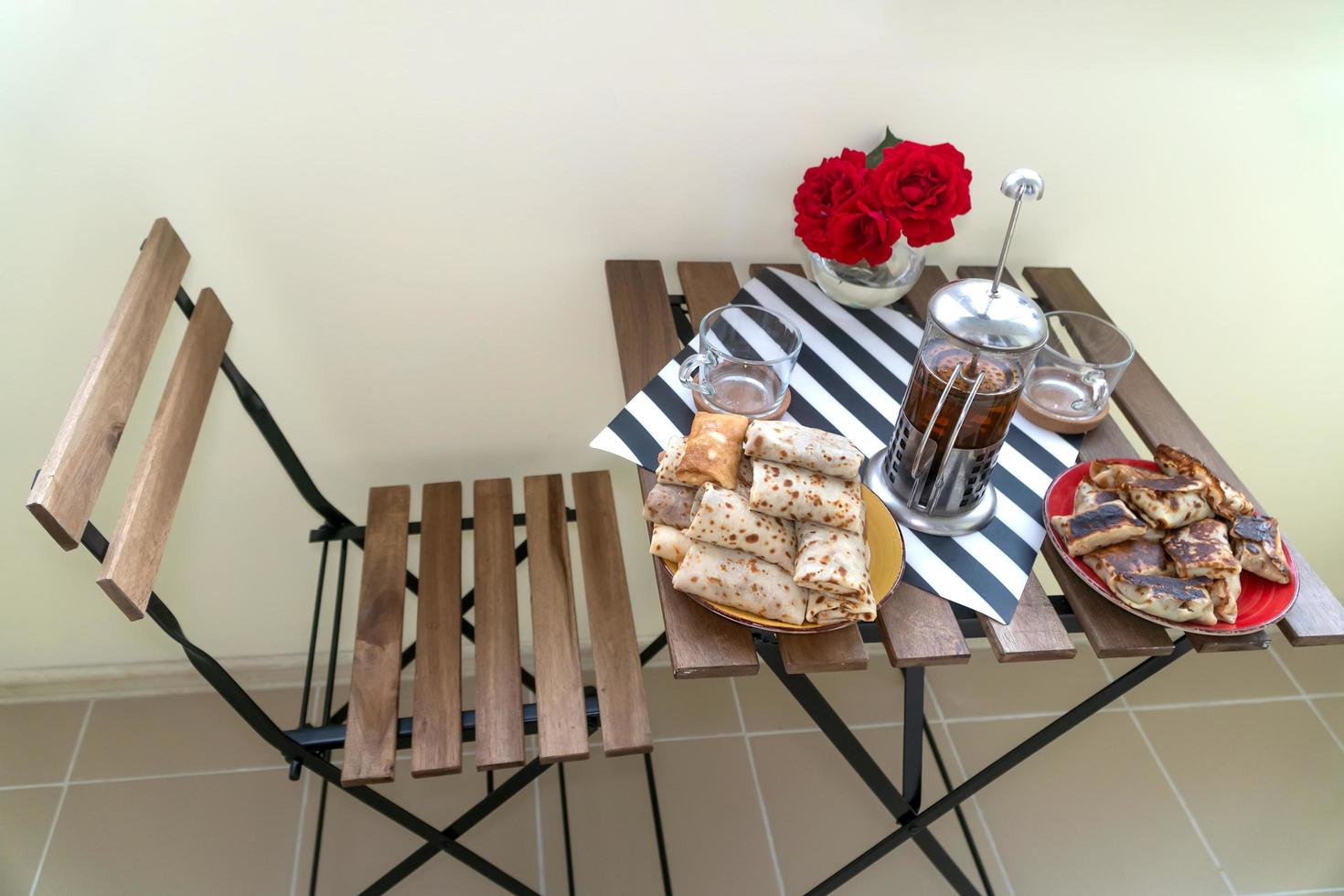 een houten stoel en een klaptafel met ontbijt op het balkon foto