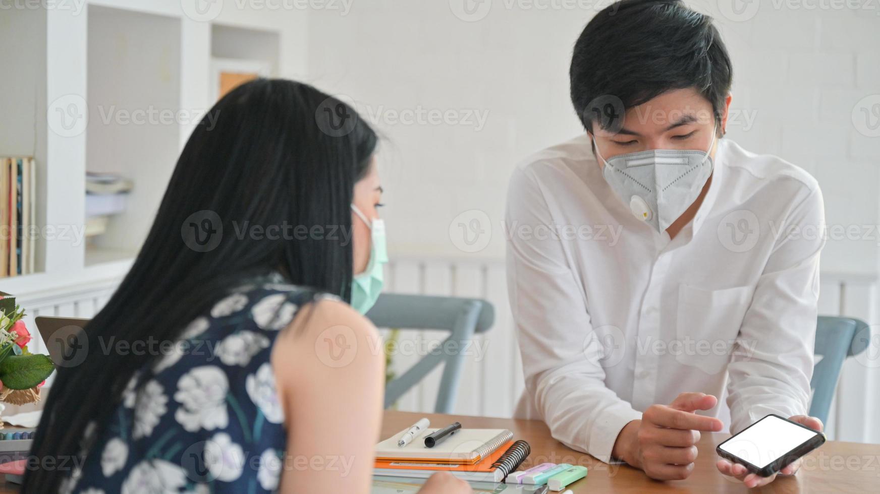 aziatische vrouwen en jonge mannen die een masker dragen, bespreken hun werk thuis om covid-19 te beschermen. foto