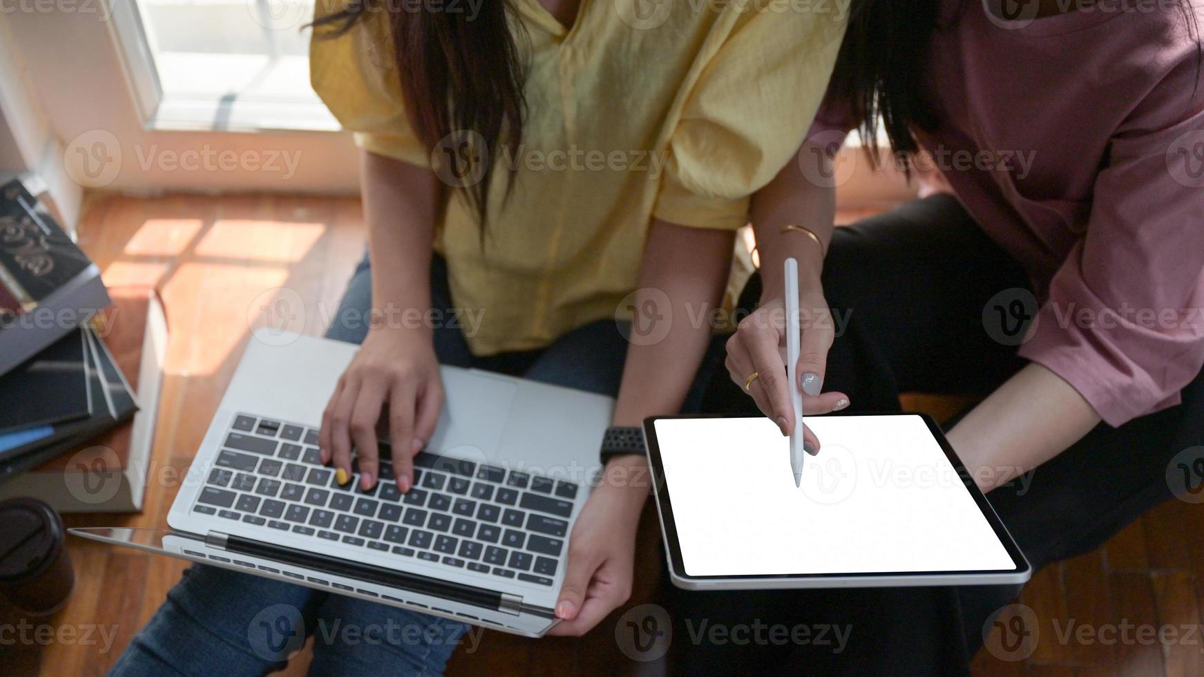 twee vrouwelijke studenten gebruiken een tablet en een laptop om thuis online te studeren om de uitbraak van het covid-19-virus te voorkomen. foto